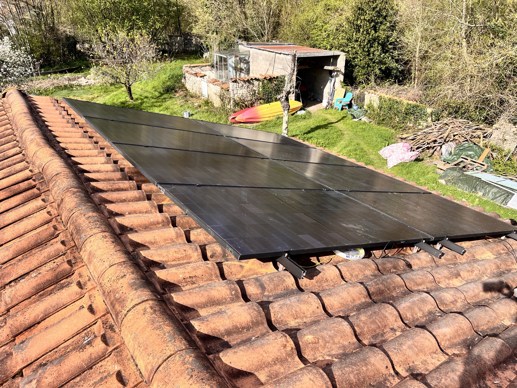 Panneaux photovoltaïques installés sur toiture en tuiles, vue plongeante sur le jardin
