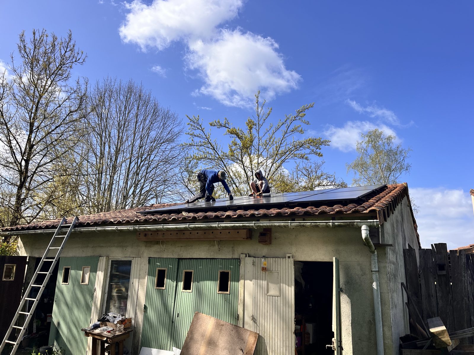 Deux installateurs posant des panneaux photovoltaïques sur le toit d'une dépendance