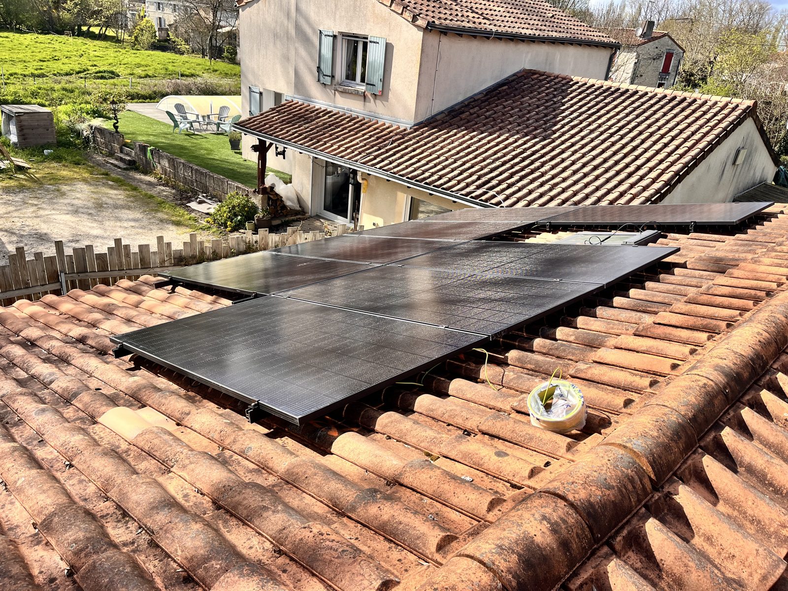 Panneaux photovoltaïques fraîchement installés sur le toit d'une maison, jardin en contrebas